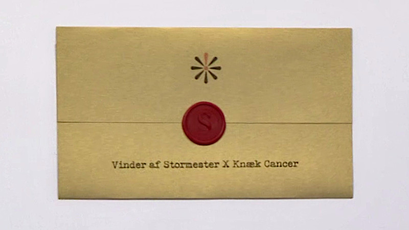 Image of the prize in this special: a framed copy of a Knæk Cancer-themed task brief, upon which the text ‘Vinder af Stormester X Knæk Cancer’ (‘Winner of Stormester X Knæk Cancer’) is printed.