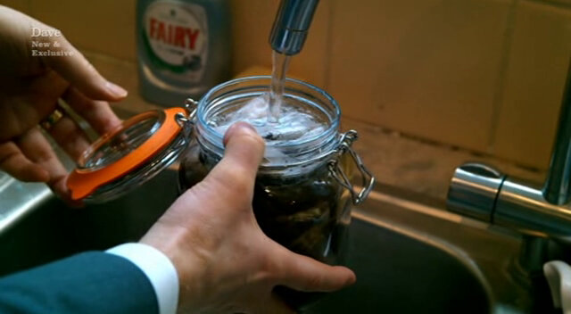 Close-up image of Frank’s hands as he fills a mason jar of teabags with water from the kitchen tap.