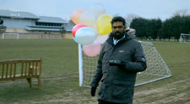 Image of Romesh Ranganathan standing next to a football pitch, holding a bunch of balloons, while completing his GPS self-portrait.