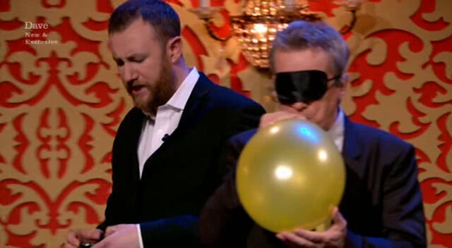 Image of Frank Skinner inflating a balloon as Alex Horne prowls in the background.