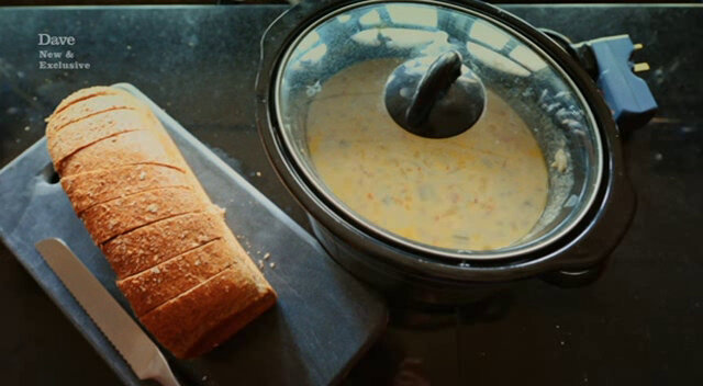 Image showing a slow cooker containing fish chowder prepared by Tim Key, next to a thickly-sliced loaf of bread on a marble cutting board.