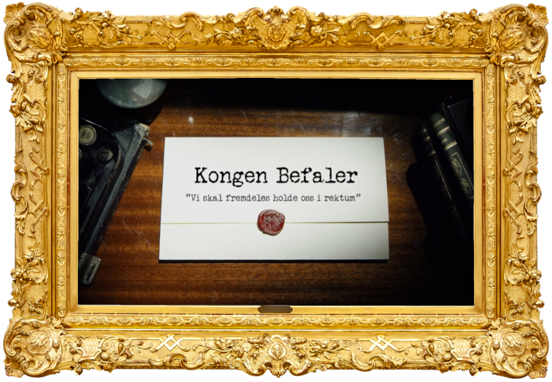 Image of the title card at the start of this episode, showing a task brief with the show title, 'Kongen Befaler', and the episode title, 'Vi skal fremdeles holde oss i rektum' ['We will still stay in the rectum'], on a wooden desk. At the edges of the image, part of a typewriter keyboard and a stack of leather-bound books can be seen.