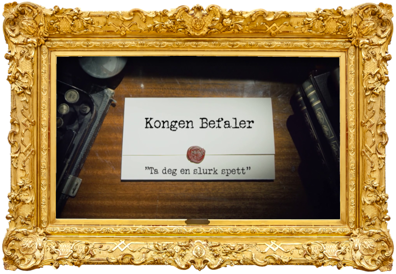 Image of the title card at the start of this episode, showing a task brief with the show title, 'Kongen Befaler', and the episode title, 'Ta deg en slurk spett' ['Take a sip of digging bar'], on a wooden desk. At the edges of the image, part of a typewriter keyboard and a stack of leather-bound books can be seen.