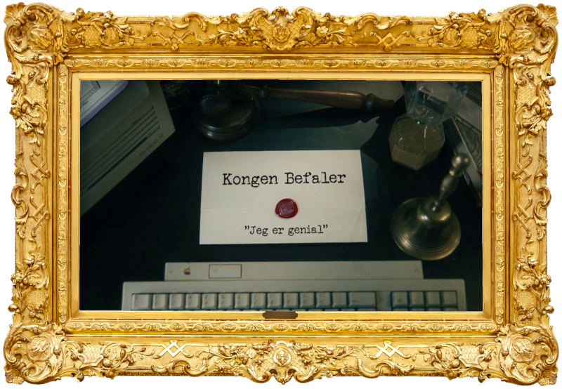 Image of the title card at the start of this episode, showing a task brief with the show title, 'Kongen Befaler', and the episode title, 'Jeg er genial' ['I'm brilliant'], on a wooden desk. Also on the desk is an old-fashioned Apple computer and keyboard, a gavel, an hourglass, and a bell.