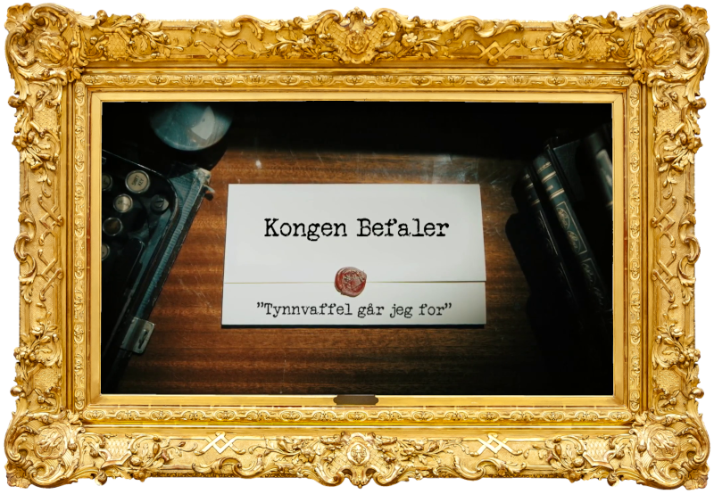 Image of the title card at the start of this episode, showing a task brief with the show title, 'Kongen Befaler', and the episode title, 'Tynnvaffel går jeg for' ['I'm going for a thin waffle'], on a wooden desk. At the edges of the image, part of a typewriter keyboard and a stack of leather-bound books can be seen.