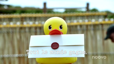 Image of a rubber duck holding a task brief in its beak (taken during the 'Fell all the ducks' task), with the episode title, 'Tout le monde gagne' ['Everyone wins'] superimposed over the top.