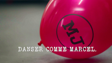 Image of an inflated red Le Maître du Jeu-branded balloon on the floor (a reference to the 'Inflate, tie, and pop the most balloons' task), with the episode title 'Danser comme Marcel' [Dance like Marcel] superimposed on it.