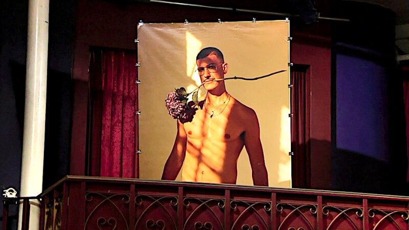 Image of the prize up for grabs in this episode: a life-sized nude poster of Tobias holding a flower in his mouth.