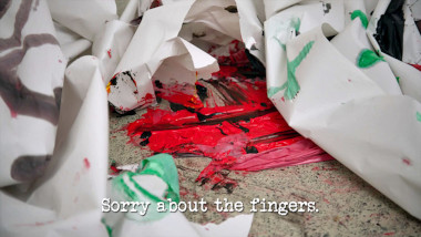 Image of some torn paper and thickly-applied paint on the floor of the lab (a reference to Aaron Chen's attempt at the 'Create and then burst through a banner' task), with the episode title, 'Sorry about the fingers', superimposed on it.