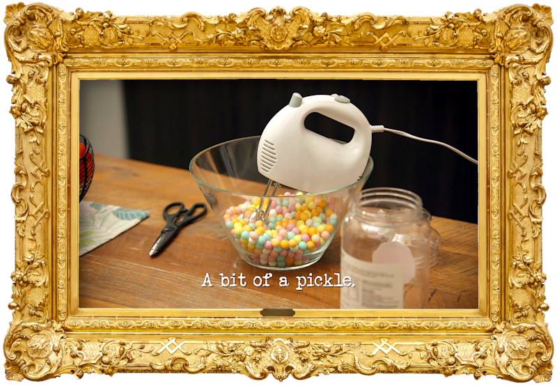 Image of an electric whisk balanced in a glass bowl of hard sweets on a kitchen counter (a reference to Aaron Chen's attempt at the ‘Make the most obnoxiously loud racket with a racquet’ task), with the episode title, ‘A bit of a pickle’, superimposed on it.