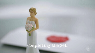Image of a wedding cake bride topper figurine in front of a task brief (a reference to the 'Make the least appropriate wedding cake' task), with the episode title, 'Completing the set', superimposed on it.