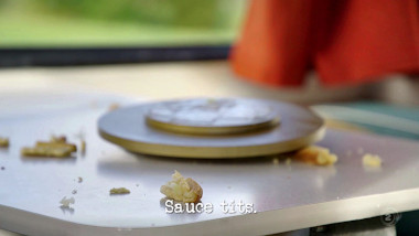 Image of the remnants of a pie on the table of the caravan (a reference to the 'Recite pi' task), with the episode title, 'Sauce tits', superimposed on it.