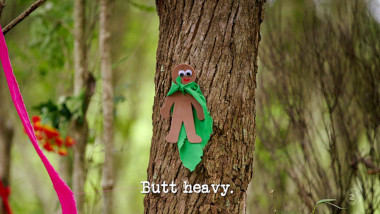 Image of a small felt man wearing a cape, attached to the trunk of a tree (a reference to the 'Enchant the forest' task), with the episode title, 'Butt heavy', superimposed on it.