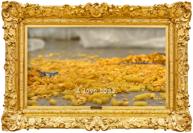 Image of a mixture of dry goods, including pasta and breakfast cereal, scattered on the floor of the lab of the Taskmaster house (a reference to Dai Henwood's attempt at the 'Do the most unpredictable thing' task), with the episode title, 'A love bomb', superimposed on it.