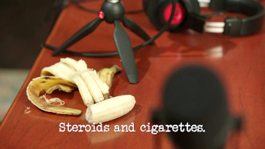 Image of a peeled and half-eaten banana pm a desk next to some microphones and headphones (a reference to the 'Record a vaguely interesting podcast' task), with the episode title, 'Steroids and cigarettes', superimposed on it.