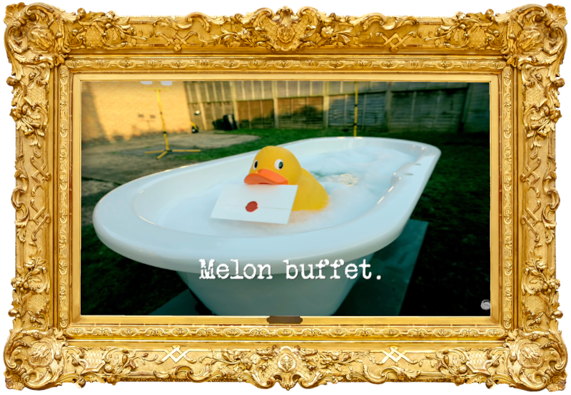 Image of a rubber duck holding a task in its bill, floating in the bathtub full of soapy water in the TaskMaster garden (taken during the 'Empty the bathtub' task), with the episode title, ‘Melon buffet’, superimposed on it.