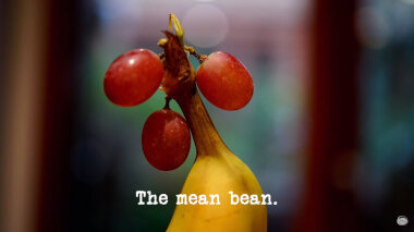 Image of three red grapes hanging off the stalk of a banana (a reference to the 'Make the most exotic fruit hat' task), with the episode title, 'The mean bean', superimposed on it.