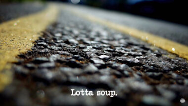 Image of a tarmac road surface with double yellow lines painted on it (presumably a reference to the traffic warden in the 'Cheer up the traffic warden' task), with the episode title, 'Lotta soup', superimposed on it.