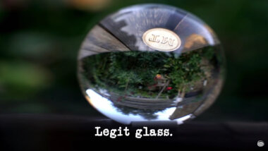 Image of the inverted view through a glass sphere (a reference to the 'Make the best and longest-lasting marble run' task), with the episode title, 'Legit glass', superimposed on it.