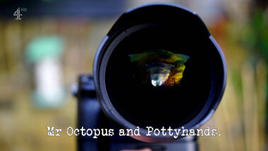 Image of a camera lens (a reference to the 'Appear as different as possible in four photos' task), with the episode title, 'Mr Octopus and Pottyhands', superimposed on it.
