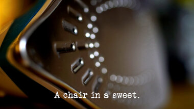 Image of the bottom of a clothes iron (a reference to the 'Land the iron on the ironing board' task), with the episode title, 'A chair in a sweet', superimposed on it.