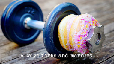 Photo of two doughnuts on a handweight (a reference to the 'Do something shocking with a doughnut' and 'Demonstrate an effective, high-intensity exercise routine' tasks), with the episode title, 'Always forks and marbles', superimposed on it.