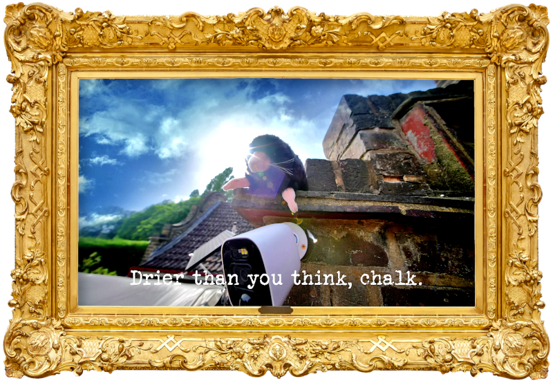 Image of a stuffed toy mole peering off the corner of the roof of the Taskmaster house, just above a security camera attached to the wall (referencing the 'Steal the statue of Archimedes' and 'Get exactly 63 points by bopping Alex on the head' tasks), with the episode title, 'Drier than you think, chalk', superimposed on it.