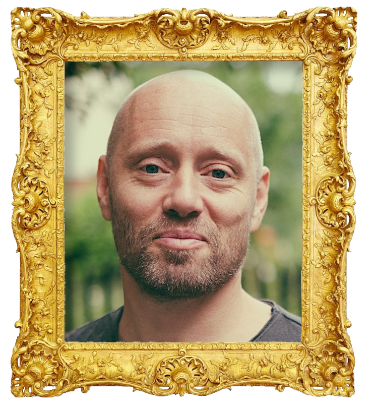 Headshot photo of Aksel Hennie surrounded with an ornate golden frame.