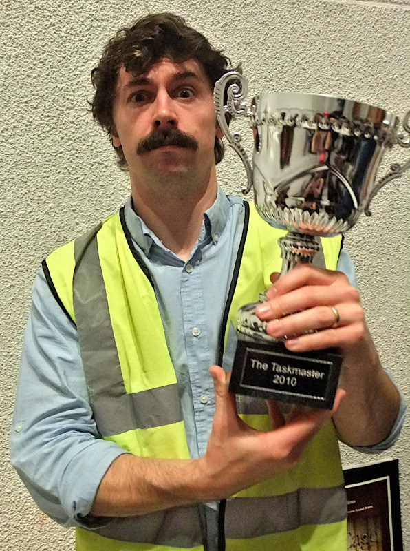 Photo of Mike Wonziak, the winner of the first Taskmaster competition, holding his trophy. [Credit: Isabelle (https://www.flickr.com/photos/diamondgeyser/)]