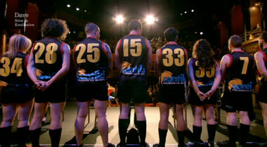 Image of the backs of about half the members of an Australian Rules Football team.