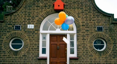 Image of the task brief being delivered to the front step of the Taskmaster house, suspended from a bunch of balloons.