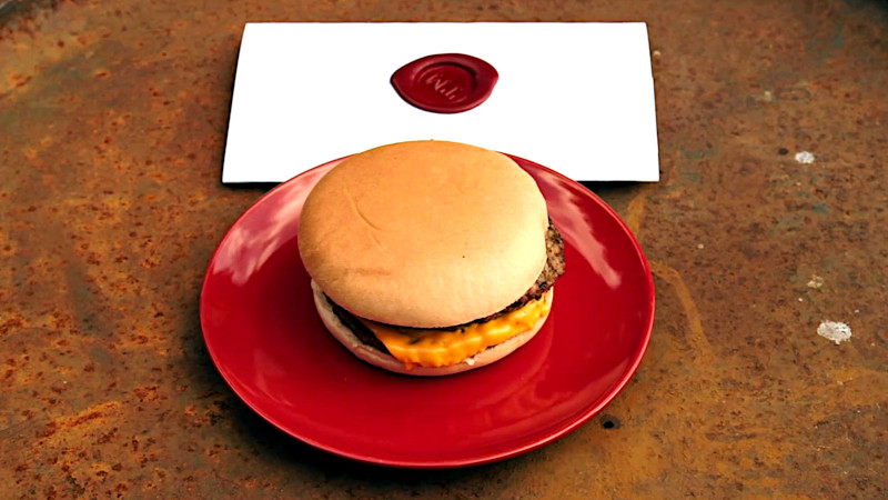 A cheeseburger on a plate next to a sealed task brief.