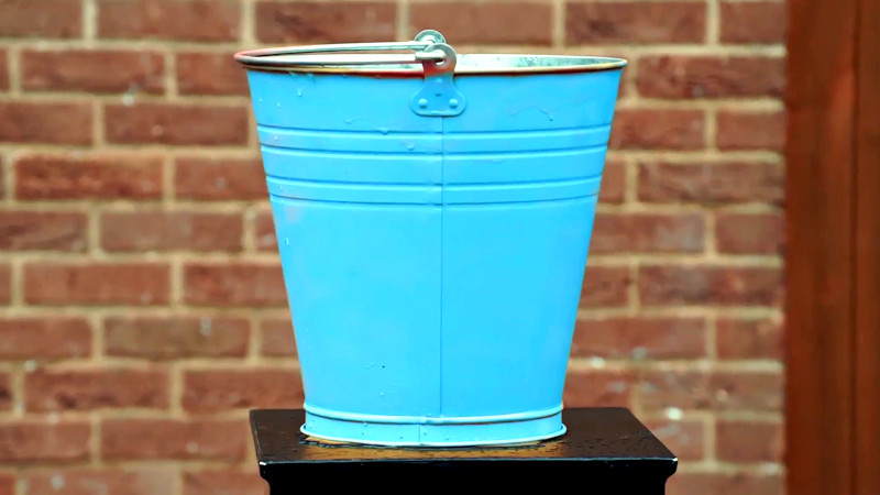A blue bucket of water on top of a plinth. A blue bucket of water on top of a plinth.