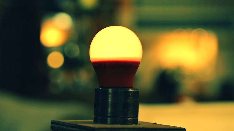 A single lightbulb embedded in a wooden platform.