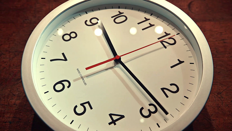 An analogue wall clock displaying the time 9:12.