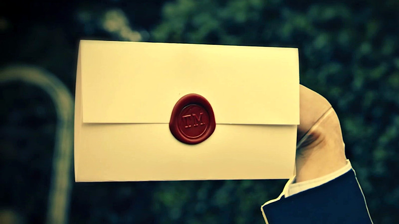 A cardboard cut-out of Alex holding the task envelope on a raised hand.