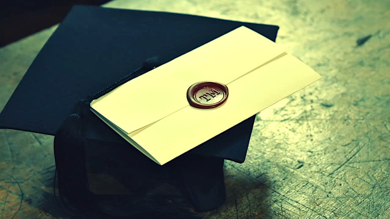 A task envelope on top of a graduation mortarboard.