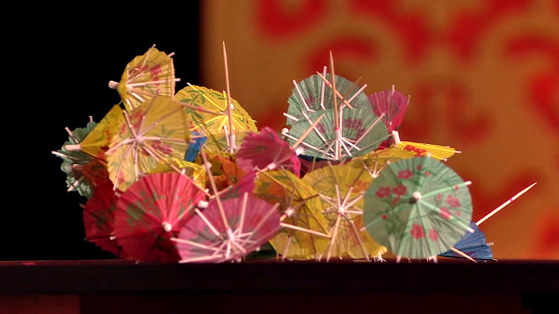 A pile of tangled cocktail umbrellas on a table surface.