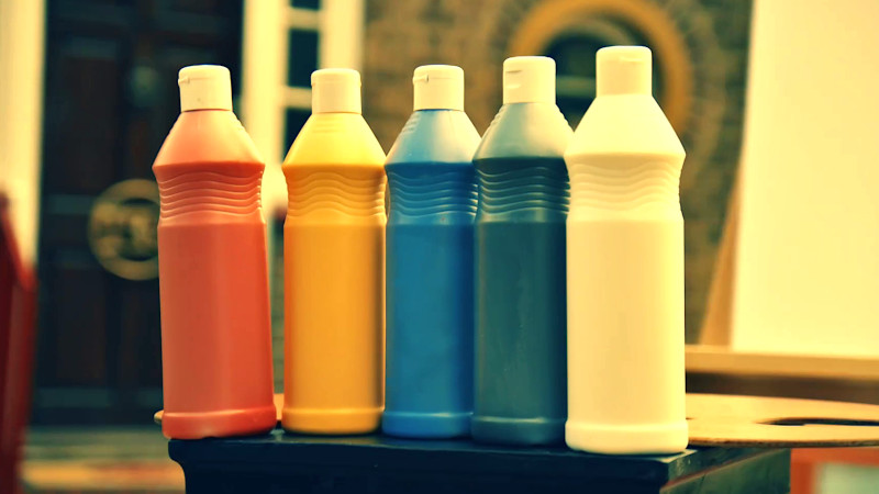 Five different colours of paints and an easel on a podium.