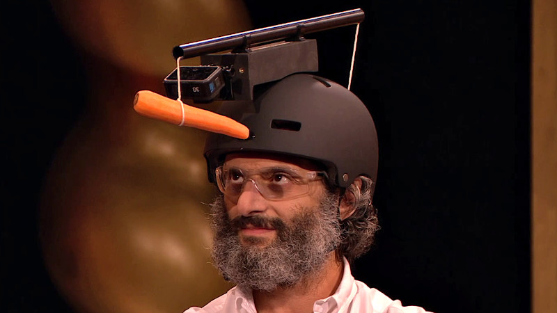Jason staring intently at a carrot suspended above his eyeline on a string suspended from the top of a Go-pro camera helmet.